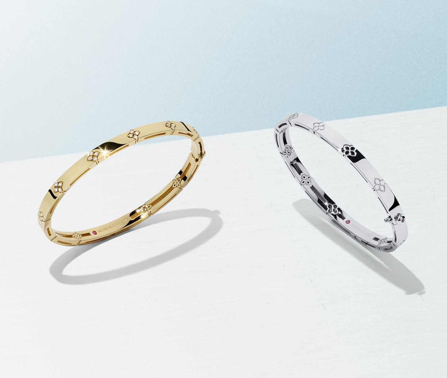 Roberto Coin Love in Verona gold bracelets on a light blue background.